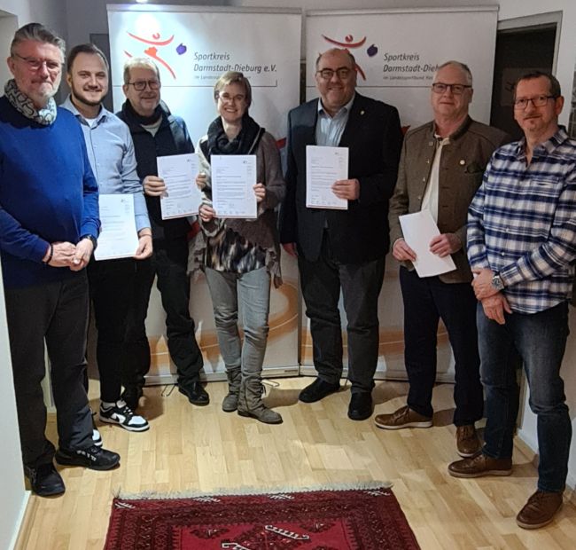 Förderbescheide an zufriedene Vereine, von links: Sportkreisvorsitzender Rafael Reißer, Vedad Turic (Rechner, FSV 1919 Groß-Zimmern), Edgar Böhm (Vorsitzender, Sektion Darmstadt-Starkenburg des DAV), Astrid Ohl (Vorstand Halle, TV 1907 Heubach), Thomas Fischbach (Kinderschutzbeauftragter, TV 1888 Jugenheim), Heinz Eucker (Oberschützenmeister, SG 1454 Babenhausen) und Norbert Weiher (Schützenmeister, SG 1454 Babenhausen).    Bild: Uwe Knecht