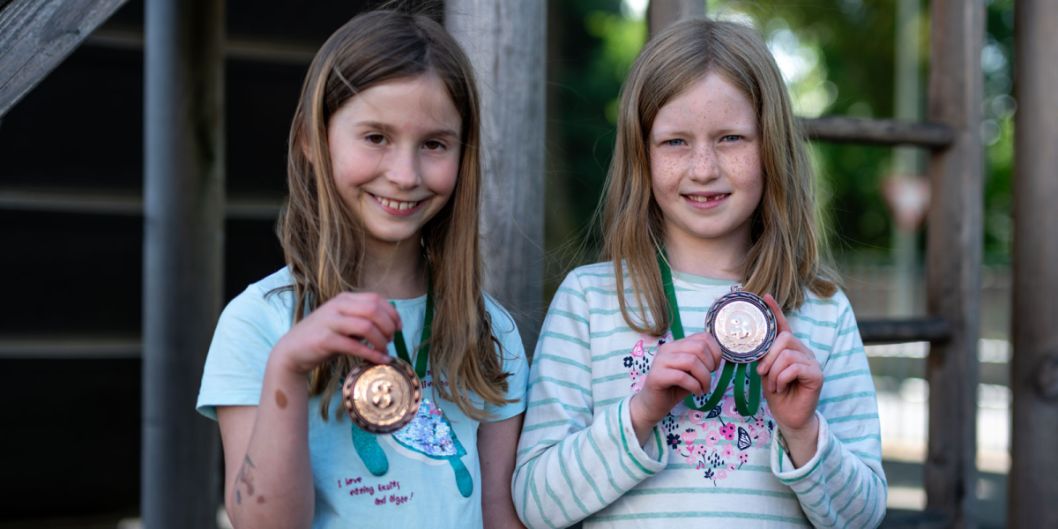 Mädchen freuen sich über ihre Medaille.