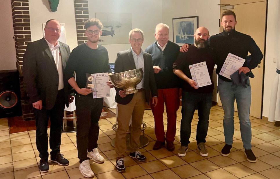 Das Foto zeigt den Präsidenten des Segelclub Edersee Guido Kalbe (links), den Präsidenten des Hessischen Seglerverbandes, Klaus-Dieter Lachmann (Mitte) und den Sieger Björn Geisler mit seiner Crew (v.l.n.r) Mattis Blum (ESV), Julian Leschinsky (SCAS) und Philipp Behrendt (ESV). Es fehlt Cedric Stiel (ESV).    Bild: Johannes Brack, Sportwart Segelclub Edersee e.V.
