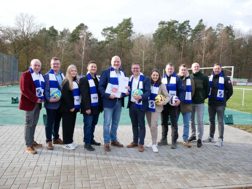SG Marbachs Vorstandssprecher Marc Backmeyer (5. v. l.) bekommt den Förderbescheid des Landkreis Fulda aus den Händen vom Ersten Kreisbeigeordneten Frederick Schmitt. Der Landkreis hat die Maßnahme mit 20 % der Gesamtkosten gefördert. Weitere 20 % kamen von der Gemeinde Petersberg gab es weitere 20 %. Aus dem Sonderinvestitionsprogramm Sportland Hessen wurde ein Zuschuss in Höhe von 30 % bereitgestellt und 5 % steuerte der lsb h dazu. Die Eigenleistung (handwerklich und finanziell) liegt bei 25 %.    Bild: Sebastian Kircher - Gemeinde Petersberg