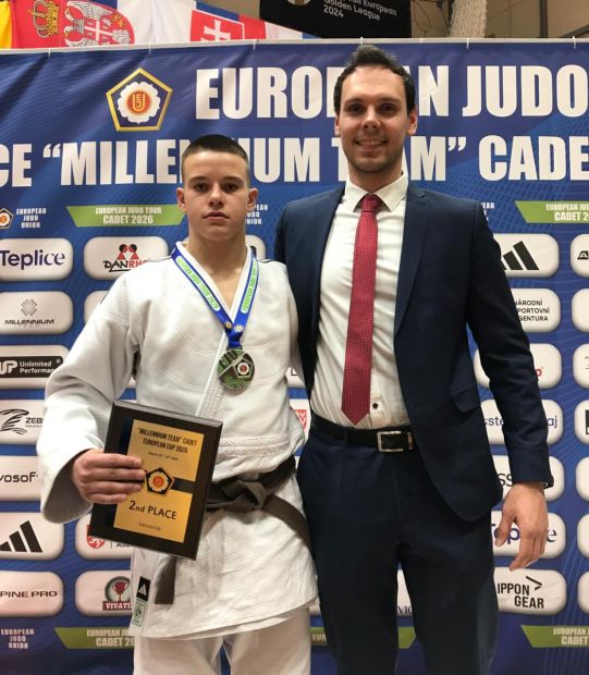 Man sieht Dmytro Matuznyi mit der Silber-Medaille neben seinem Coach