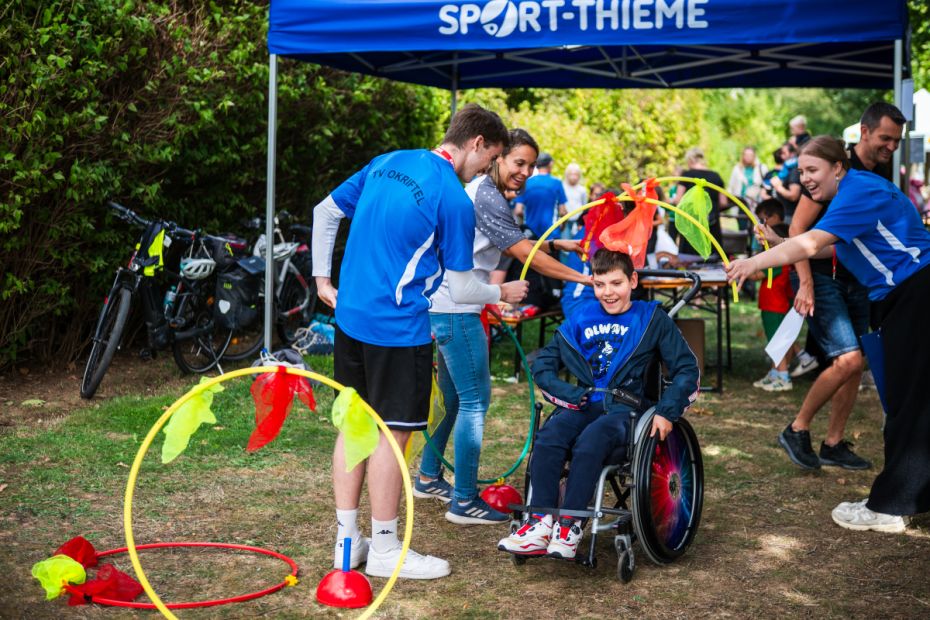 Rolli-Fahrer fährt durch dekorierte halbe Gymnastikreifen.