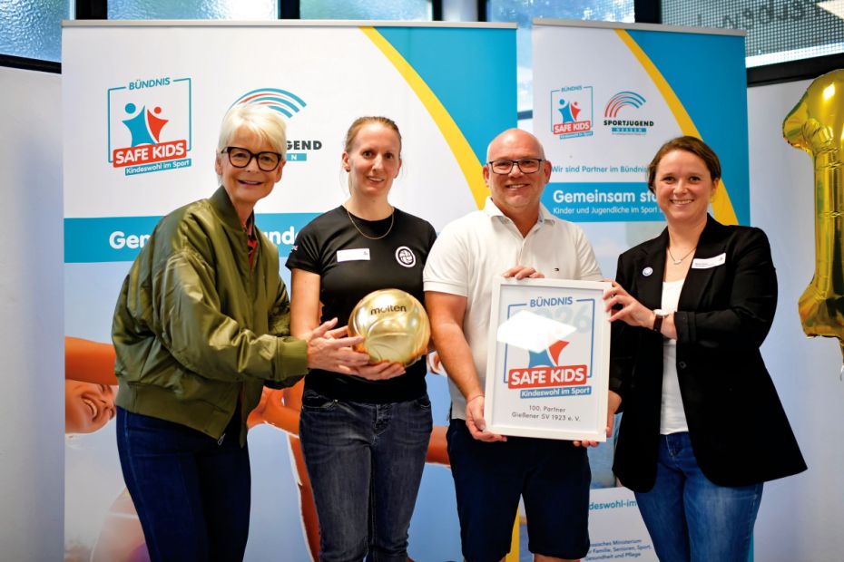 Feierliche Übergabe des symbolischen Volleyballs zur 100. Bündnispartnerschaft des Gießener SV durch die Sportbeauftragte Ann Kathrin Linsenhoff an die Kindeswohl-Ansprechperson Katrin Eger und Vorstandsvorsitzender Jürgen Boldt, der von Malin Hoster das Bündnissiegel erhält.