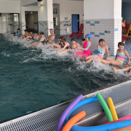 Bewegungskoordinator Marius Hamel zeigt den Kindern eine Übung zur Wassergewöhnung: Mit den Füßen ins Becken strampeln, Spritzwasser erleben und spielerisch Wasserwiderstand, Strömungen und das Element Wasser kennenlerne.                Bild: Sportkreis Waldeck-Frankenberg