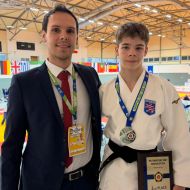 Man sieht Aaron Keller mit der Silber-Medaille neben seinem Coach 