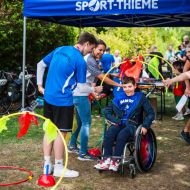 Rolli-Fahrer fährt durch dekorierte halbe Gymnastikreifen.